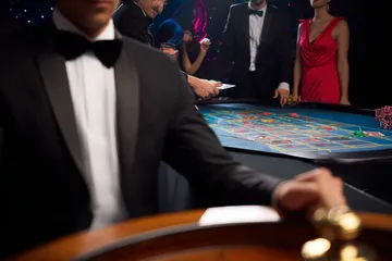 A professional dealer in a tuxedo greeting players at the roulette table, symbolizing the authentic live casino feel at JILI7979.