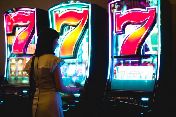 A woman smiling while playing online games on her laptop, surrounded by neon casino elements, showcasing JILI7979’s diverse game collection.